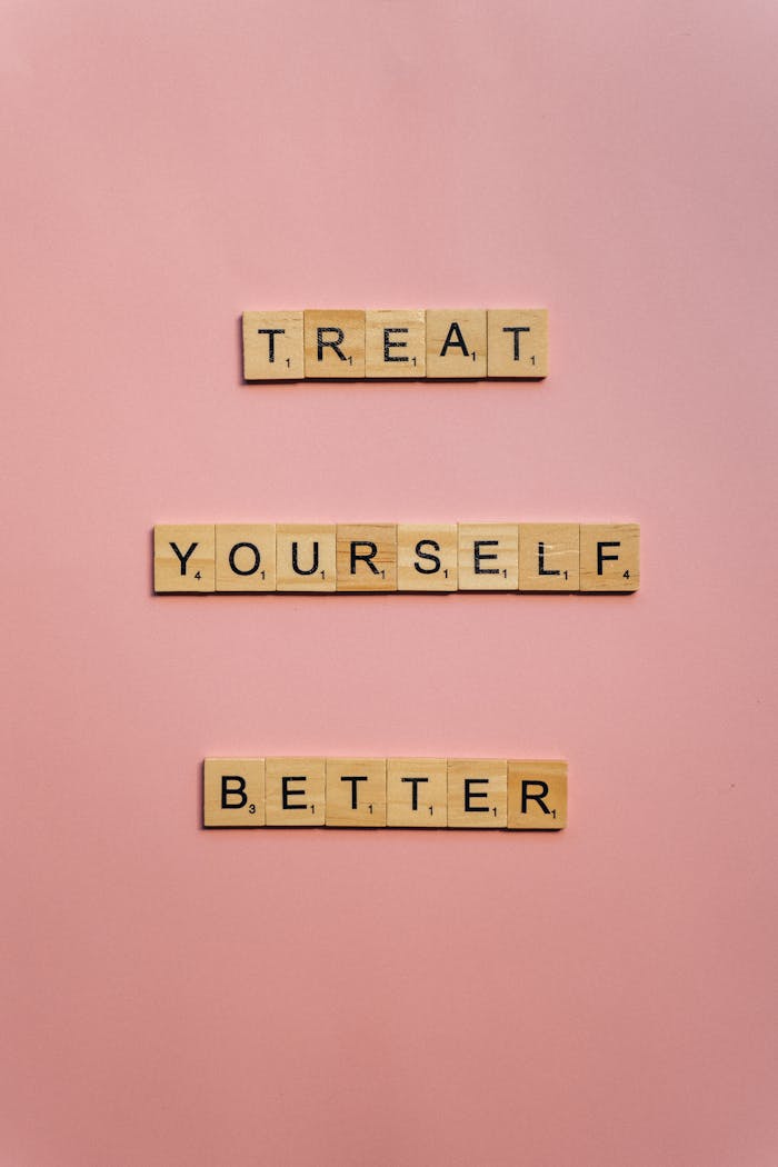 Scrabble tiles spelling 'Treat Yourself Better' on a pink background.